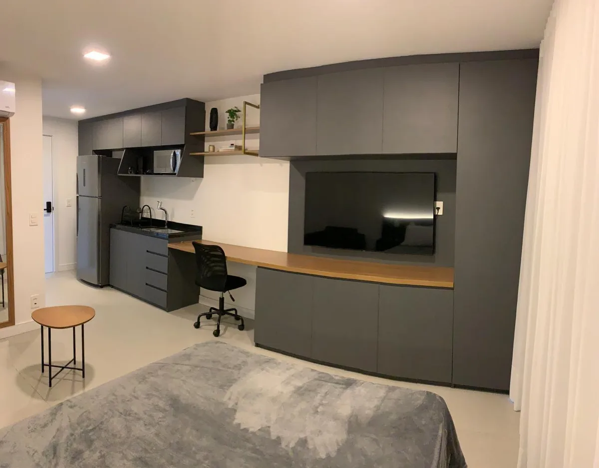 Studio com home office, kitchenette e painel de TV